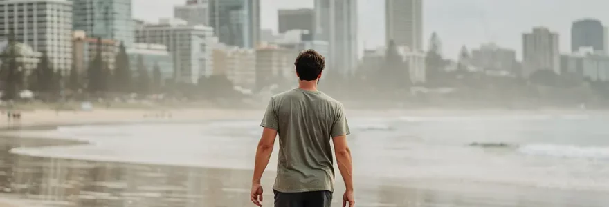 Jeune adulte marchant sur une plage australienne avec skyline urbaine en arrière-plan